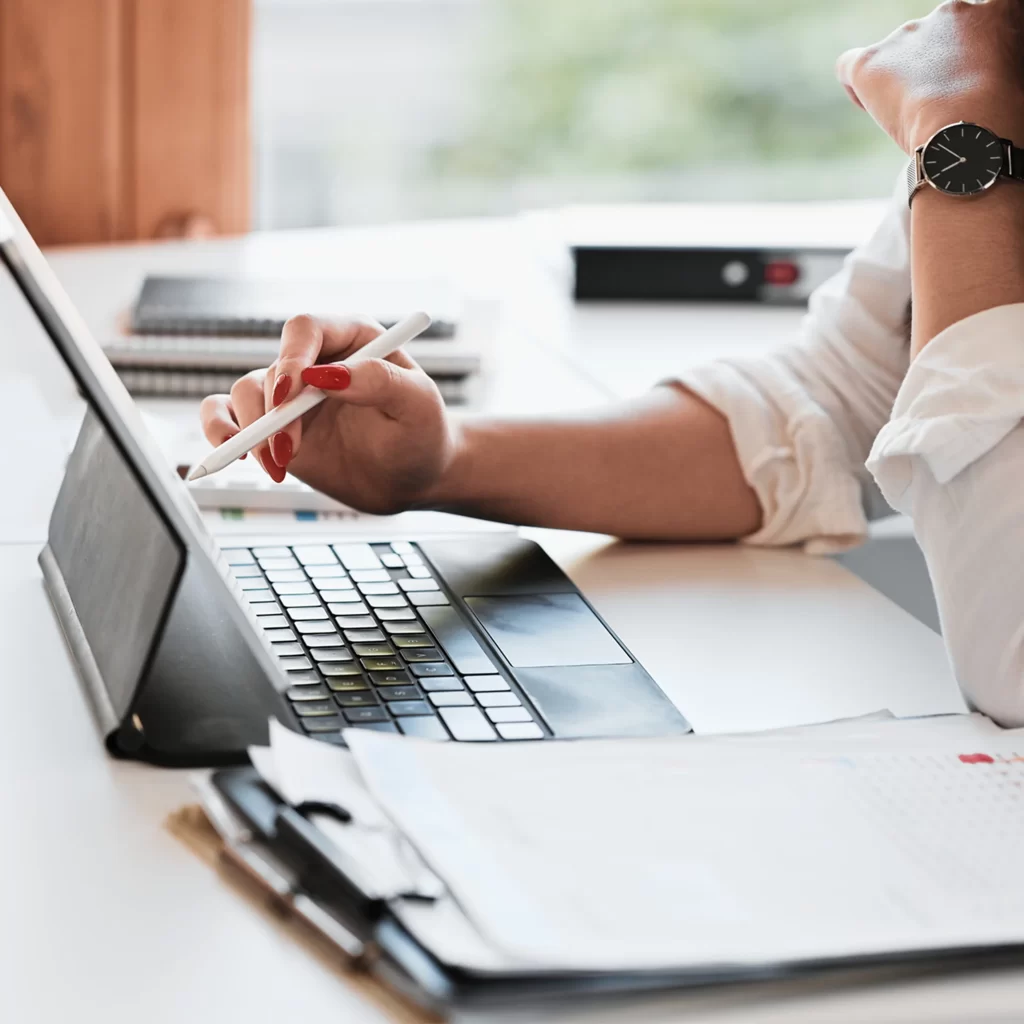Women or person working at desk on IPad with clipboard binder and white pen